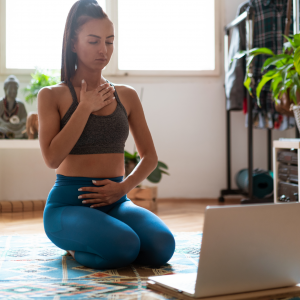 Woman practising a private online yoga session at home using a laptop for live virtual guidance.
