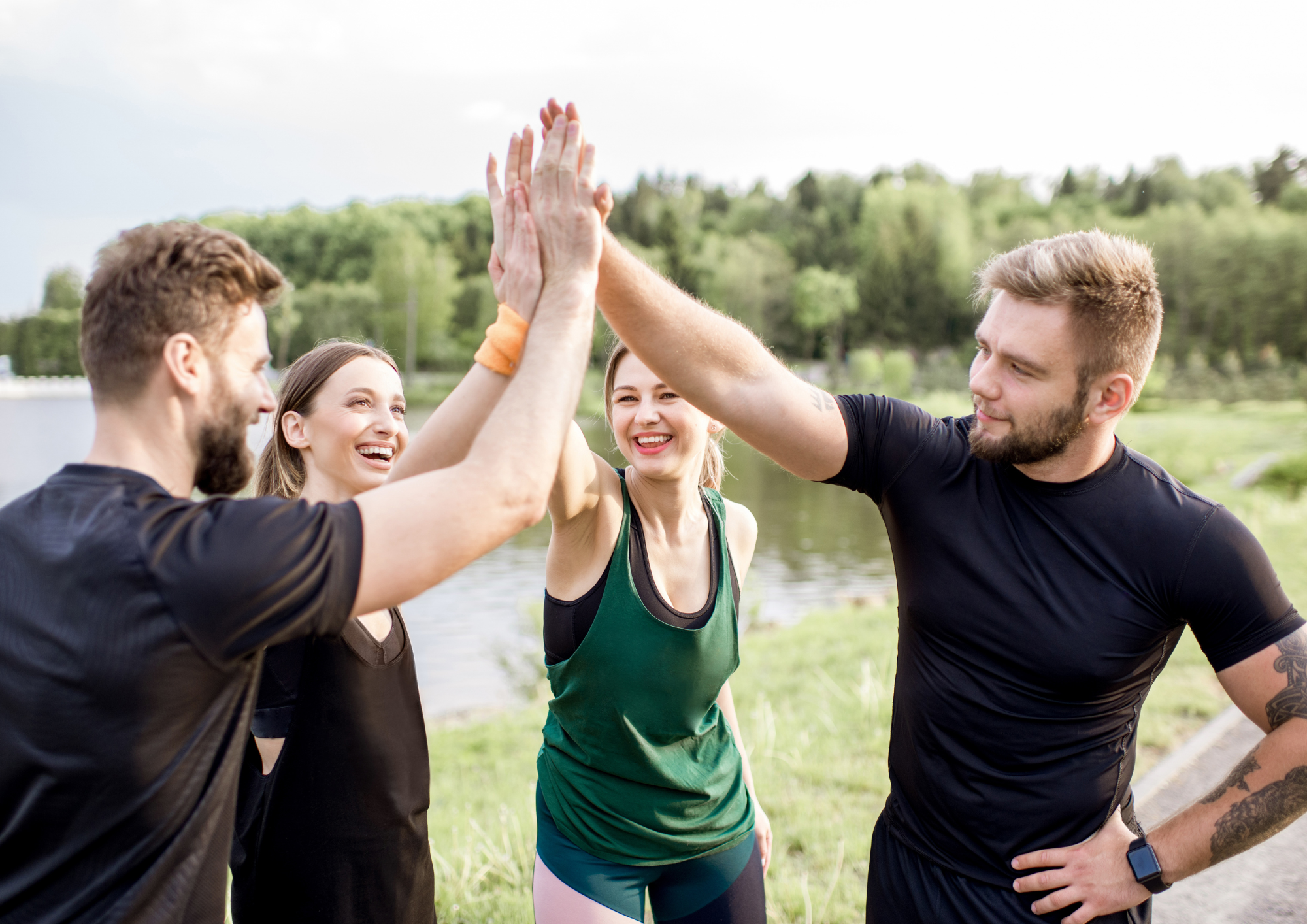 A group of colleagues standing outdoors in nature, holding hands in a circle, fostering connection, trust, and shared presence during a corporate wellbeing experience.