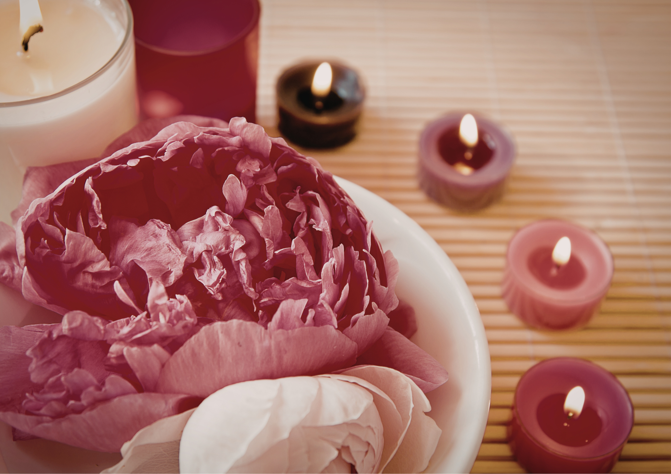 Soft flowers and lit candles creating a calm and nurturing space for a chakra massage and energy healing session