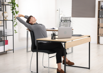 A woman performing front body, shoulders and arms stretch on the back of a chair