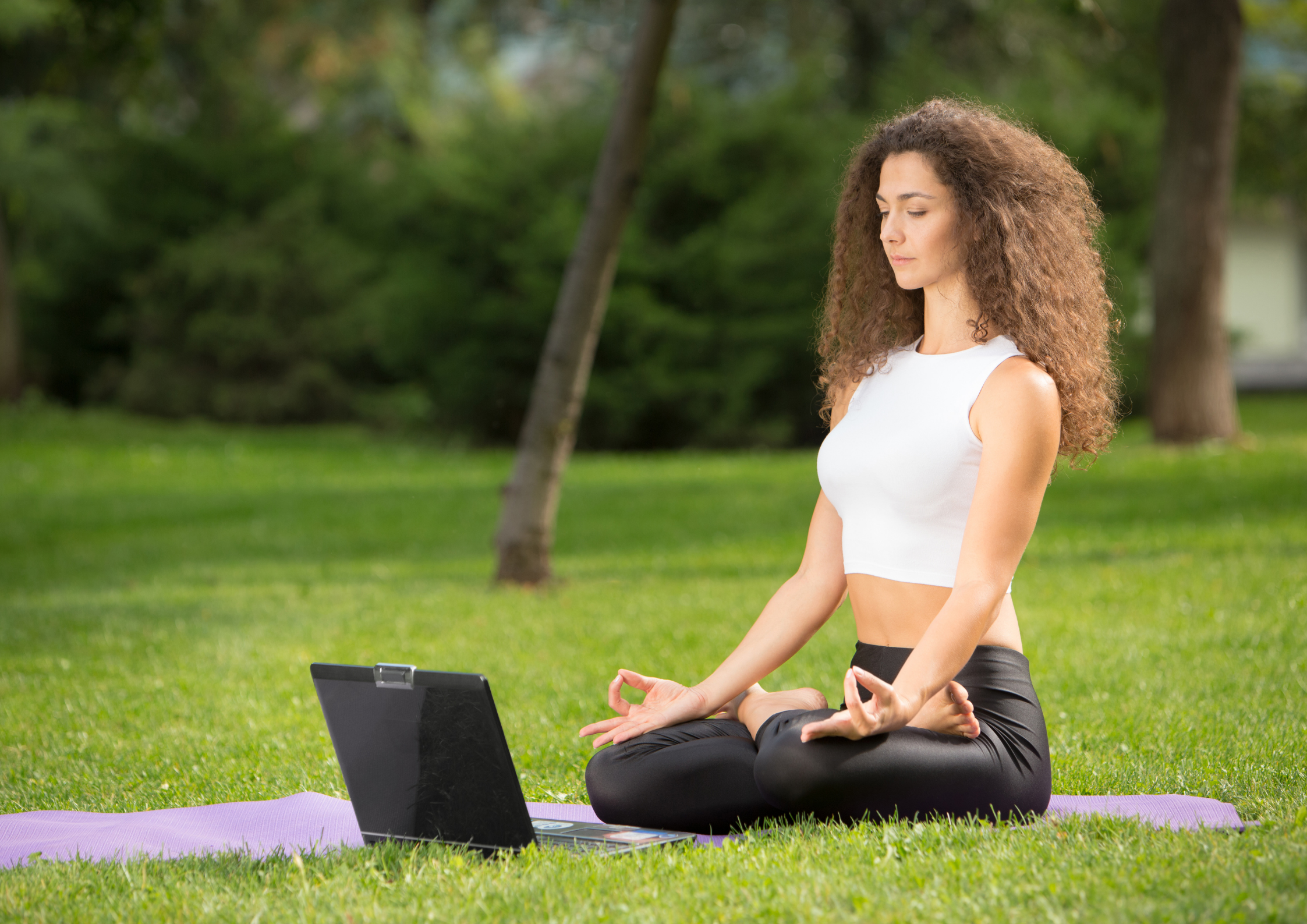 Woman practicing yoga online outdoors while traveling